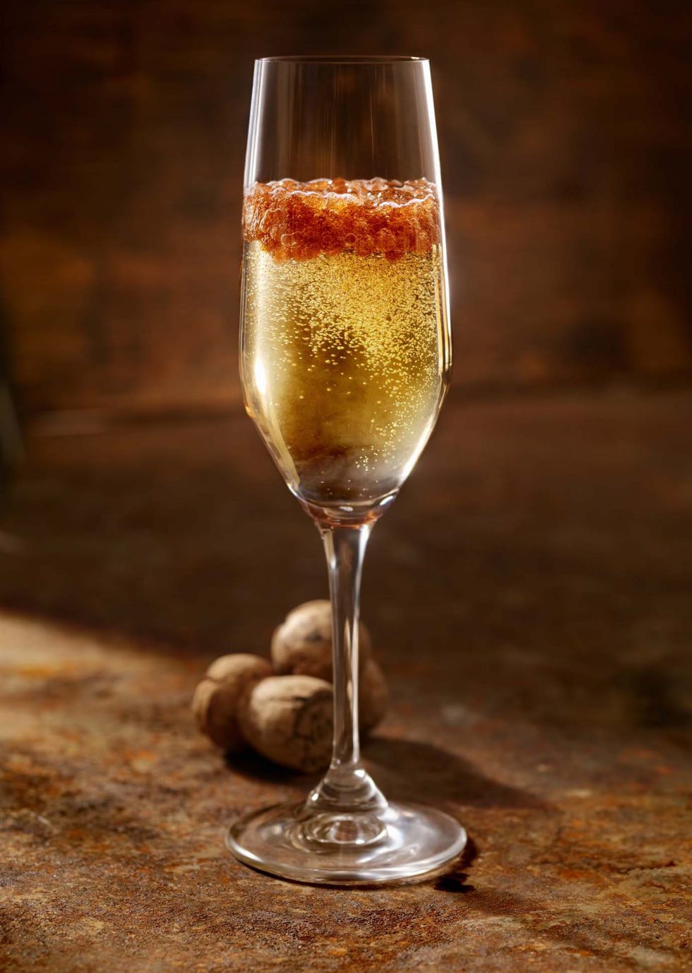 Calgary Beverage Photographer. A Glass of bubbly full of berries on rustic backdrop.
