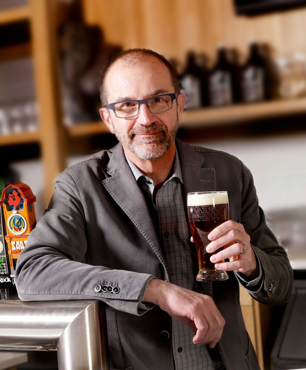 Calgary People Photographer. Man leaning on bar with pint of beer in hand.