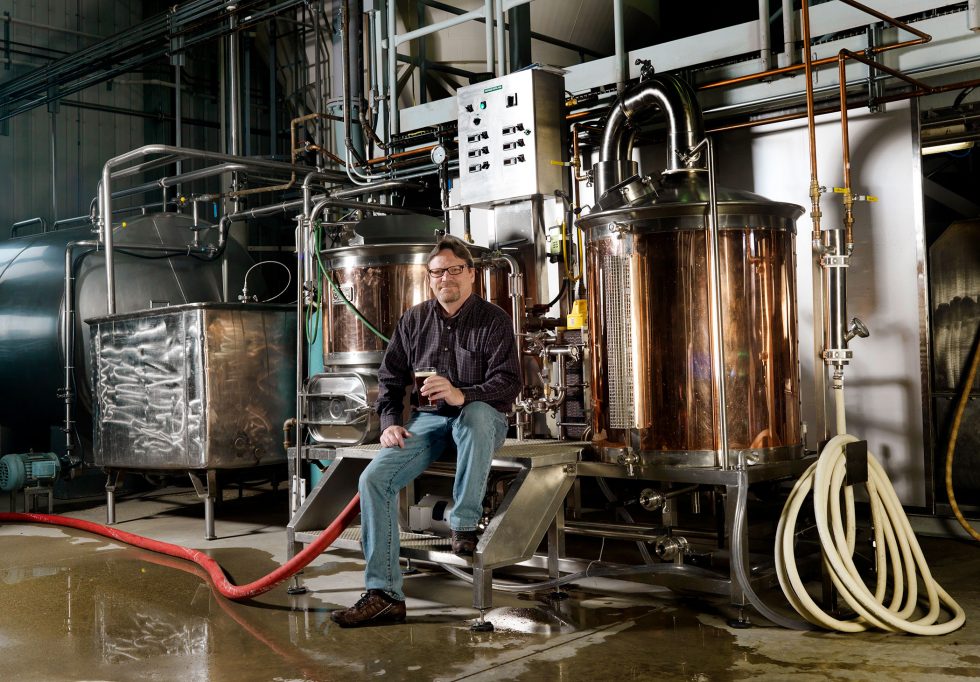 Calgary People Photographer. Man sitting in brewery with beer in hand.