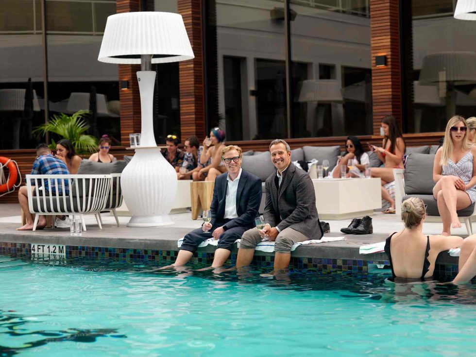 Calgary People Photographer. Two men at the pool with others. Hotel Arts.
