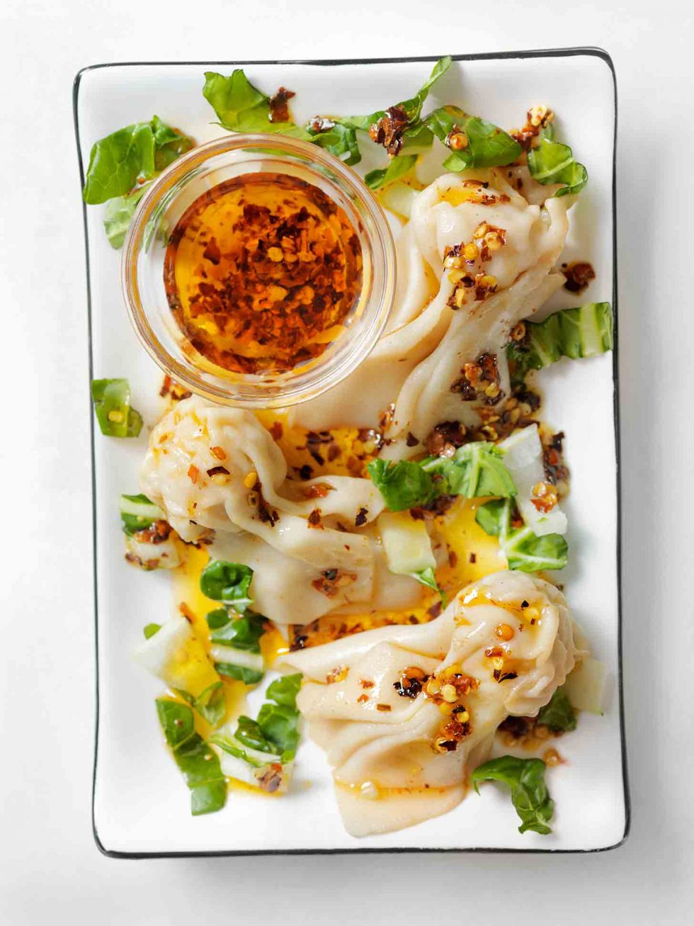 Calgary food photography. Cultural dish of wontons with chili oil and greens garnish.
