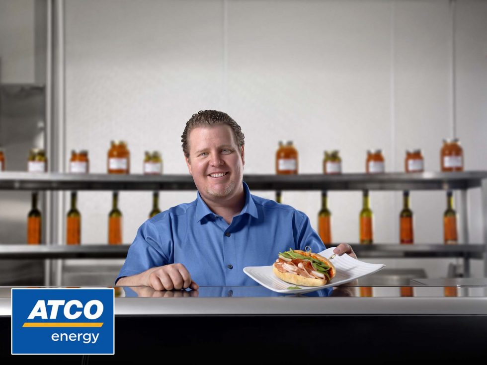 Calgary People Photography. A happy dude serving up a loaded sandwich from the kitchen.